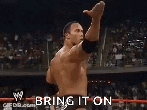 A Wrestler Is Raising His Fist In The Air In Front Of A Crowd And Says `` Bring It On '' . GIF