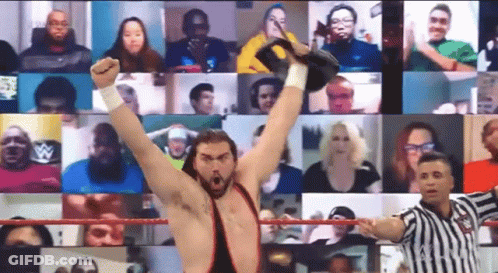A Wrestler Is Raising His Fist In The Air In Front Of A Crowd While A Referee Looks On . GIF