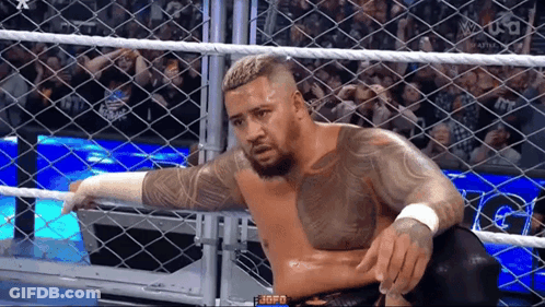 A Wrestler Is Sitting In A Cage During A Match . GIF