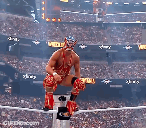A Wrestler Is Sitting On A Rope In Front Of A Crowd With Xfinity Advertisements In The Background GIF