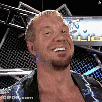 A Wrestler Is Smiling In Front Of A Wrestling Federation Sign GIF
