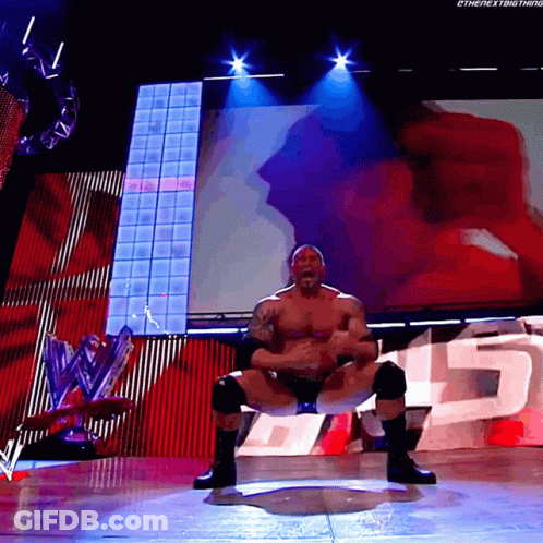 A Wrestler Is Squatting Down On A Stage With The Number 15 In The Background GIF