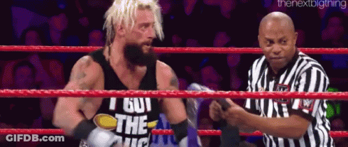 A Wrestler Is Standing In A Ring With A Referee . GIF