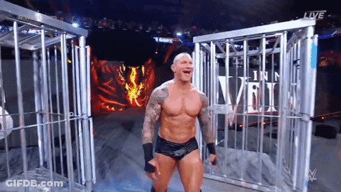 A Wrestler Is Standing In Front Of A Cage And Screaming . GIF