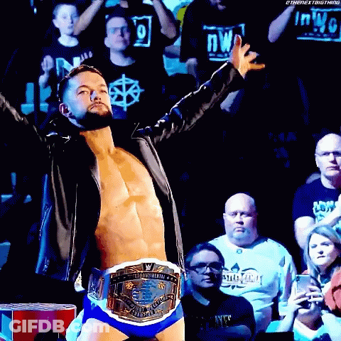 A Wrestler Is Standing In Front Of A Crowd Wearing A World Heavyweight Wrestling Championship Belt . GIF