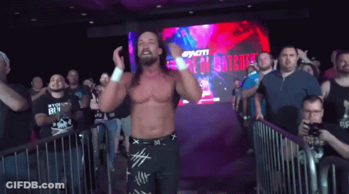 A Wrestler Is Standing In Front Of A Crowd With A Sign That Says ' I 'M A Winner ' GIF