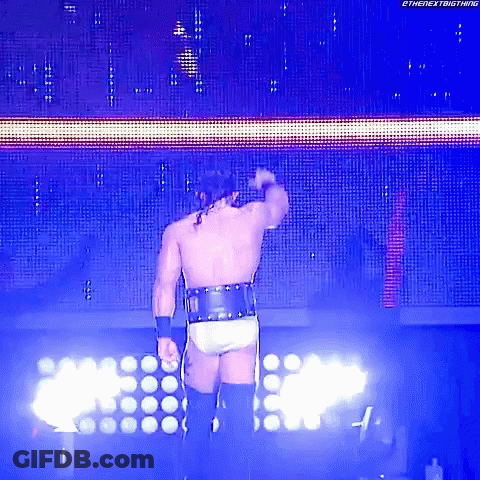 A Wrestler Is Standing In Front Of A Screen That Says The Nextbigthing GIF