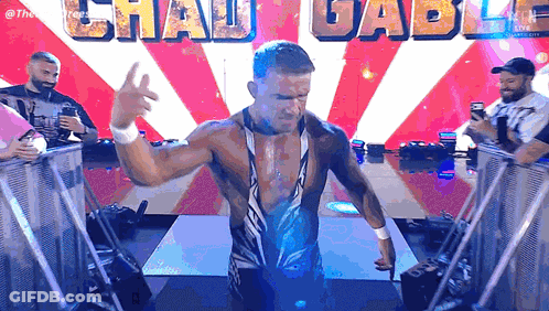 A Wrestler Is Standing In Front Of A Sign That Says Chau Gabu GIF