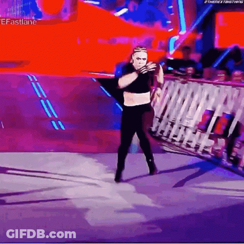 A Wrestler Is Standing On A Stage In Front Of A Crowd And Holding A Rope . GIF