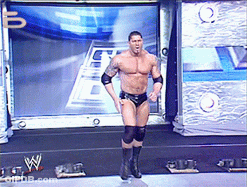 A Wrestler Is Standing On A Stage In Front Of A Large Screen With The Letter W On It GIF