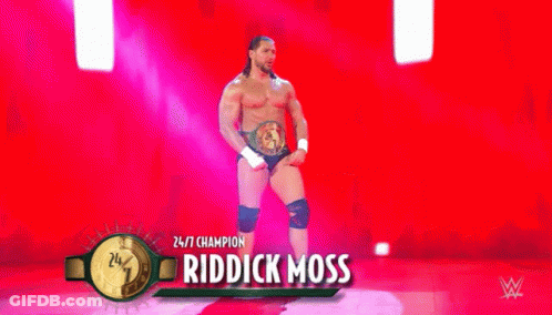 A Wrestler Is Standing On A Stage Wearing A Belt And Knee Pads . GIF