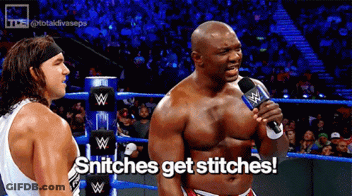 A Wrestler Is Talking Into A Microphone While Another Wrestler Looks On And Says Snitches Get Stitches GIF