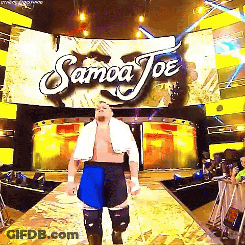 A Wrestler Is Walking Down A Ramp In Front Of A Large Screen That Says Samoa Joe . GIF