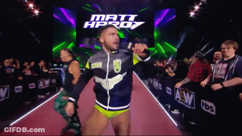 A Wrestler Is Walking Down A Red Carpet In Front Of A Sign That Says Matt Hprdy GIF