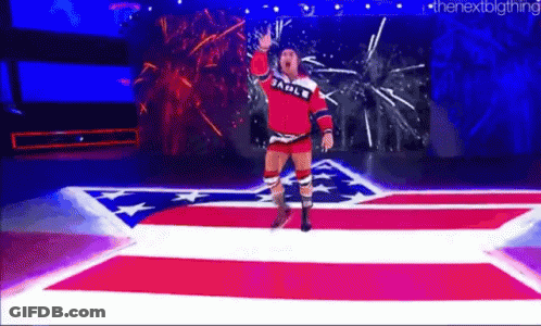 A Wrestler Is Walking Down A Red , White , And Blue Carpet On A Stage . GIF