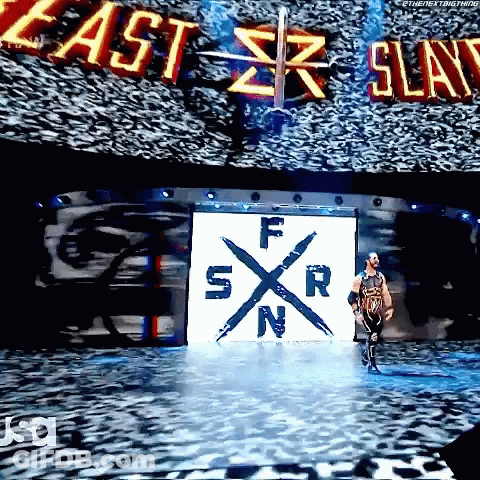 A Wrestler Is Walking Down A Stage With A Large Screen Behind Him That Says East Slay GIF