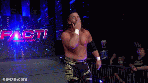 A Wrestler Is Walking In Front Of A Sign That Says Impact Wrestling . GIF