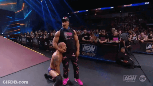 A Wrestler Kneeling Down In Front Of A Aew Banner GIF