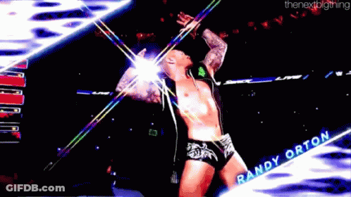 A Wrestler Named Randy Orton Is Standing On A Stage With His Arms Outstretched GIF