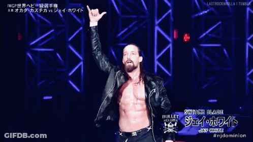 A Wrestler Named Switch Blade Is Standing On A Stage With His Arms In The Air GIF