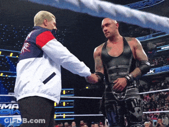A Wrestler Shakes Hands With A Referee In A Ring That Has The Word Emma On It GIF