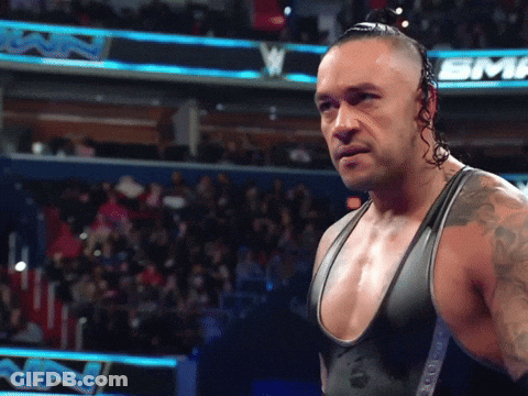 A Wrestler Stands In Front Of A Sign That Says Sinclair GIF