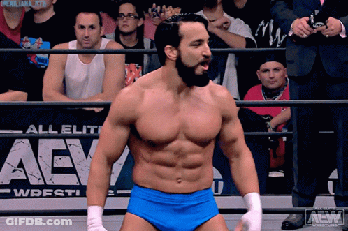 A Wrestler Stands In Front Of An Aew Sign GIF