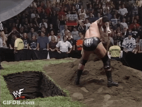 A Wrestler Wearing A Black Shorts With The Word Gear On It Stands In The Dirt GIF