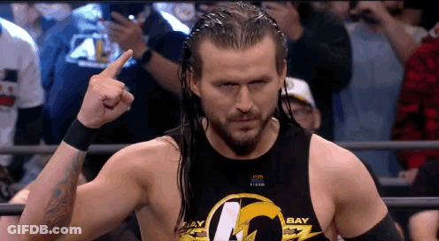 A Wrestler Wearing A Black Tank Top That Says Bay Is Giving The Middle Finger GIF
