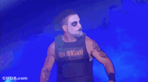 A Wrestler Wearing A Black Vest With The Word Lost On It Is Standing In Front Of A Blue Background . GIF
