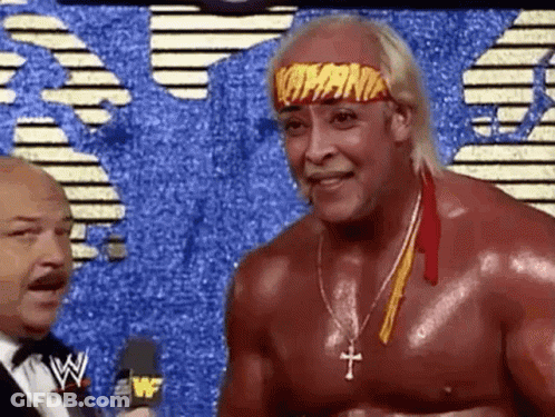 A Wrestler Wearing A Headband With The Word Hogan On It Is Talking To A Man In A Suit . GIF