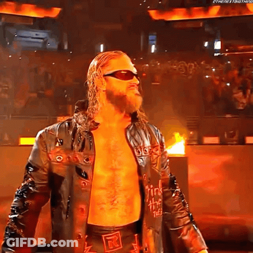 A Wrestler Wearing Sunglasses And A Leather Jacket Is Standing In Front Of A Crowd . GIF