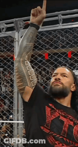 A Wrestler With A Tattoo On His Arm Holds Up His Fist In The Air GIF