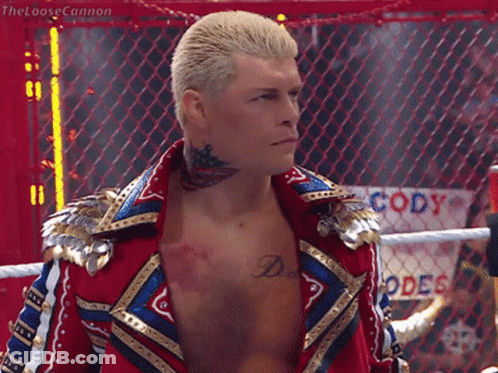 A Wrestler With A Tattoo On His Neck Is Standing In Front Of A Fence That Says Cody GIF
