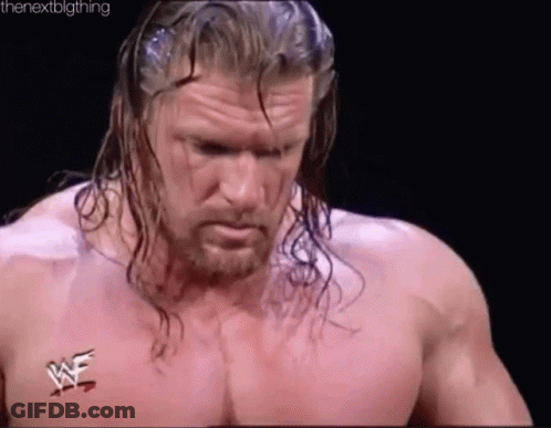 A Wrestler With Long Hair And A Beard Is Standing In A Ring Without A Shirt . GIF