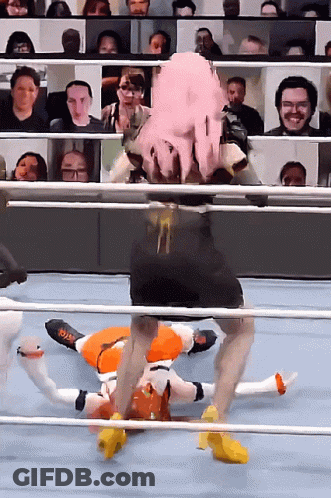 A Wrestler With Pink Hair Is Laying On The Ground In A Ring GIF