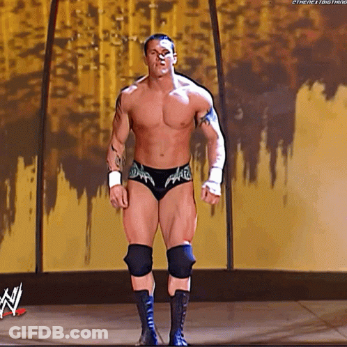 A Wrestler Without A Shirt Is Standing On A Stage With A WWE Logo In The Background . GIF