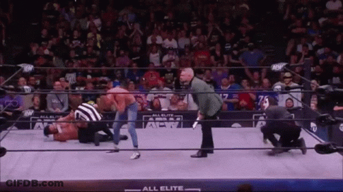 A Wrestling Match Is Being Held In A Ring With A Referee . GIF