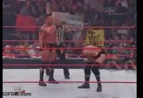 A Wrestling Match Is Being Held In A Ring With A Referee Standing Behind It . GIF