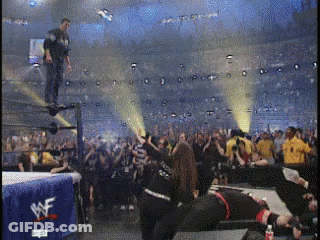 A Wrestling Match Is Being Played In A Stadium With A Wwe Banner In The Background GIF