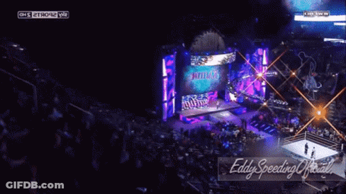 A Wrestling Match Is Being Shown On A Large Screen And The Words Eddy Speeding Official Are On The Bottom Right GIF