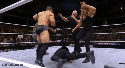 A Wrestling Match Is Going On In A Ring With A Crowd Watching . GIF