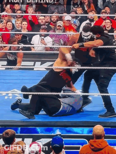 A Wrestling Match Is Going On In Front Of A Crowd With One Man Wearing A Shirt That Says ' Biker ' GIF