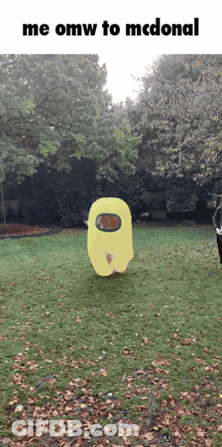 A Yellow Among Us Character Is Standing In The Grass GIF