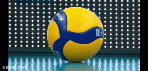 A Yellow And Blue Mikasa Volleyball Is Sitting On The Floor GIF
