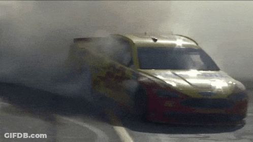 A Yellow And Red Race Car With Smoke Coming Out Of The Windshield GIF