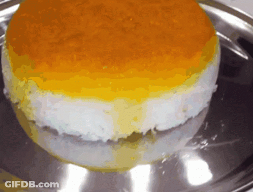 A Yellow And White Cake Is On A Silver Tray GIF