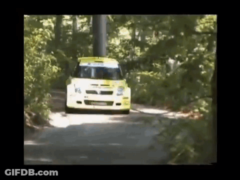 A Yellow And White Car Is Driving Down A Road Surrounded By Trees GIF