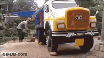 A Yellow And White Tata Truck With A Man Standing In Front Of It GIF