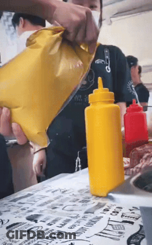 A Yellow Bottle Of Mustard Is Sitting On A Table GIF